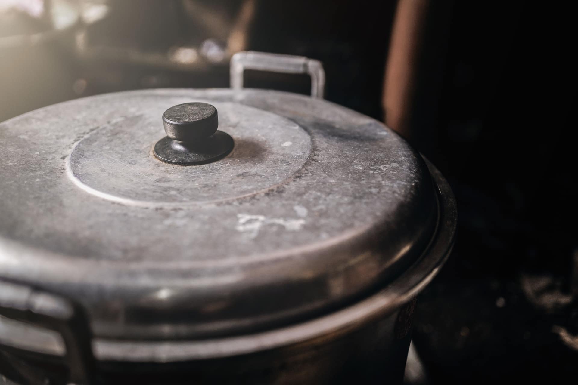 An old metal cooking pot with a black handle in a rustic kitchen