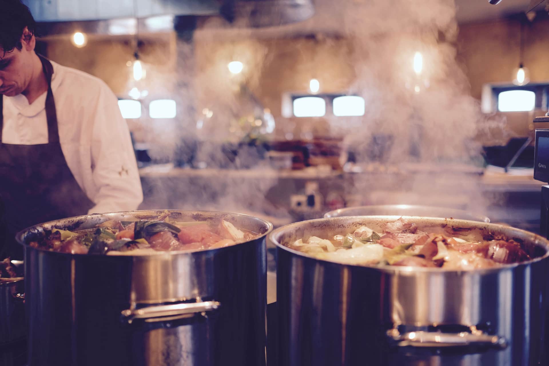 Large pots steaming on a range in a working kitchen
