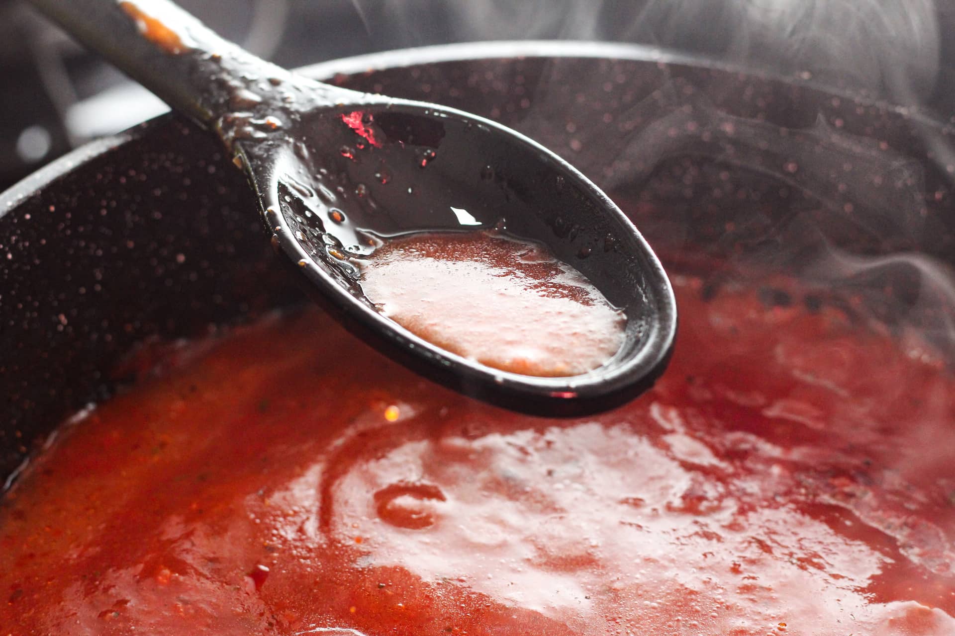 Tomato sauce cooking in a pan with a ladle