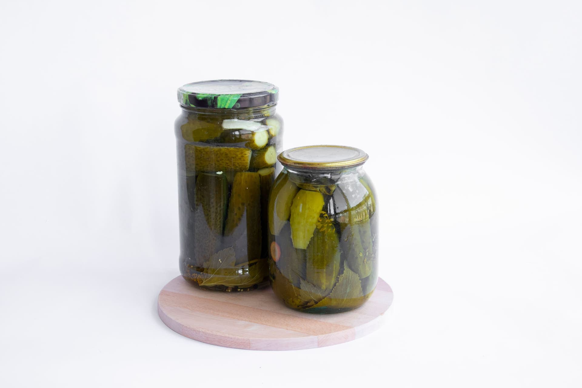 Jars of pickled cucumbers and vegetables on a dark surface