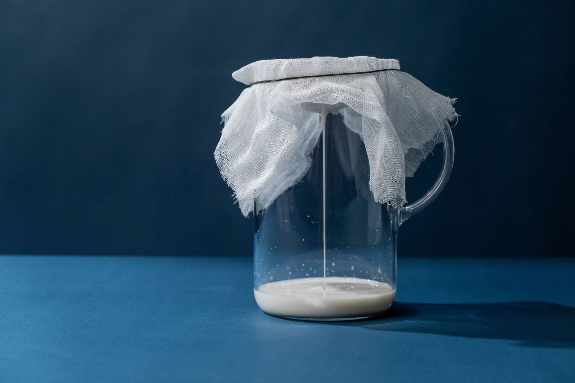 Liquid straining through cheesecloth into a glass pitcher