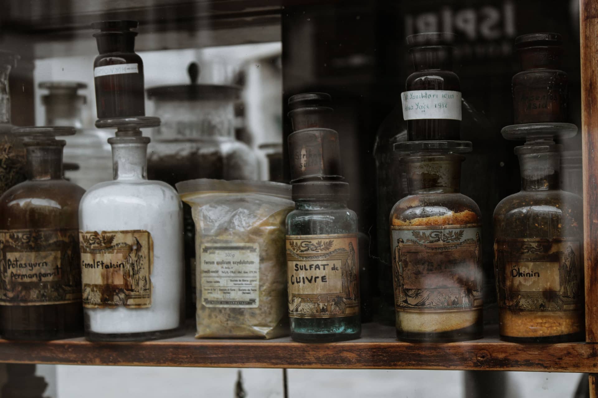 Vintage bottles with handwritten labels on a wooden shelf
