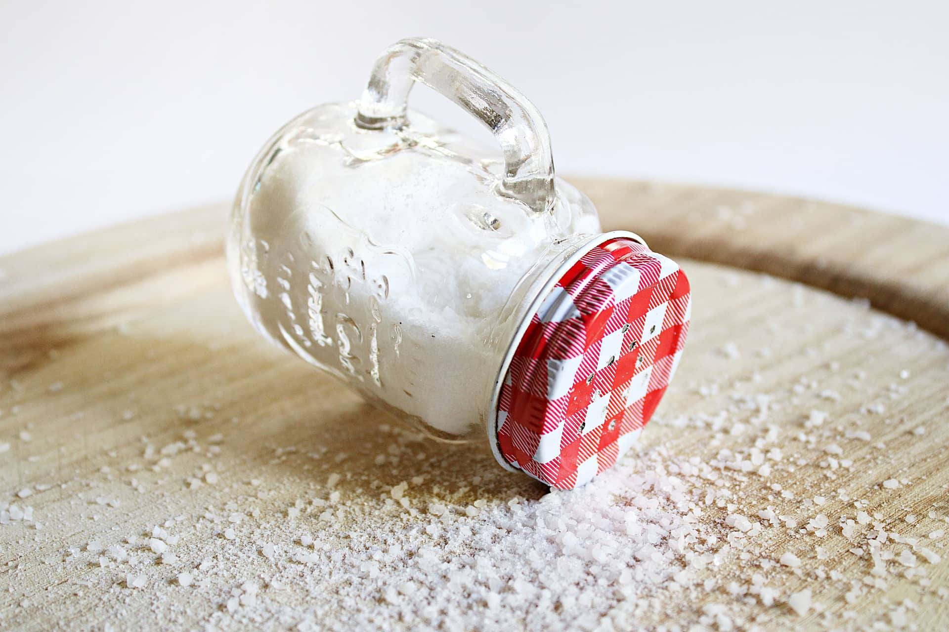 An overturned mason jar with a red lid on a wooden surface