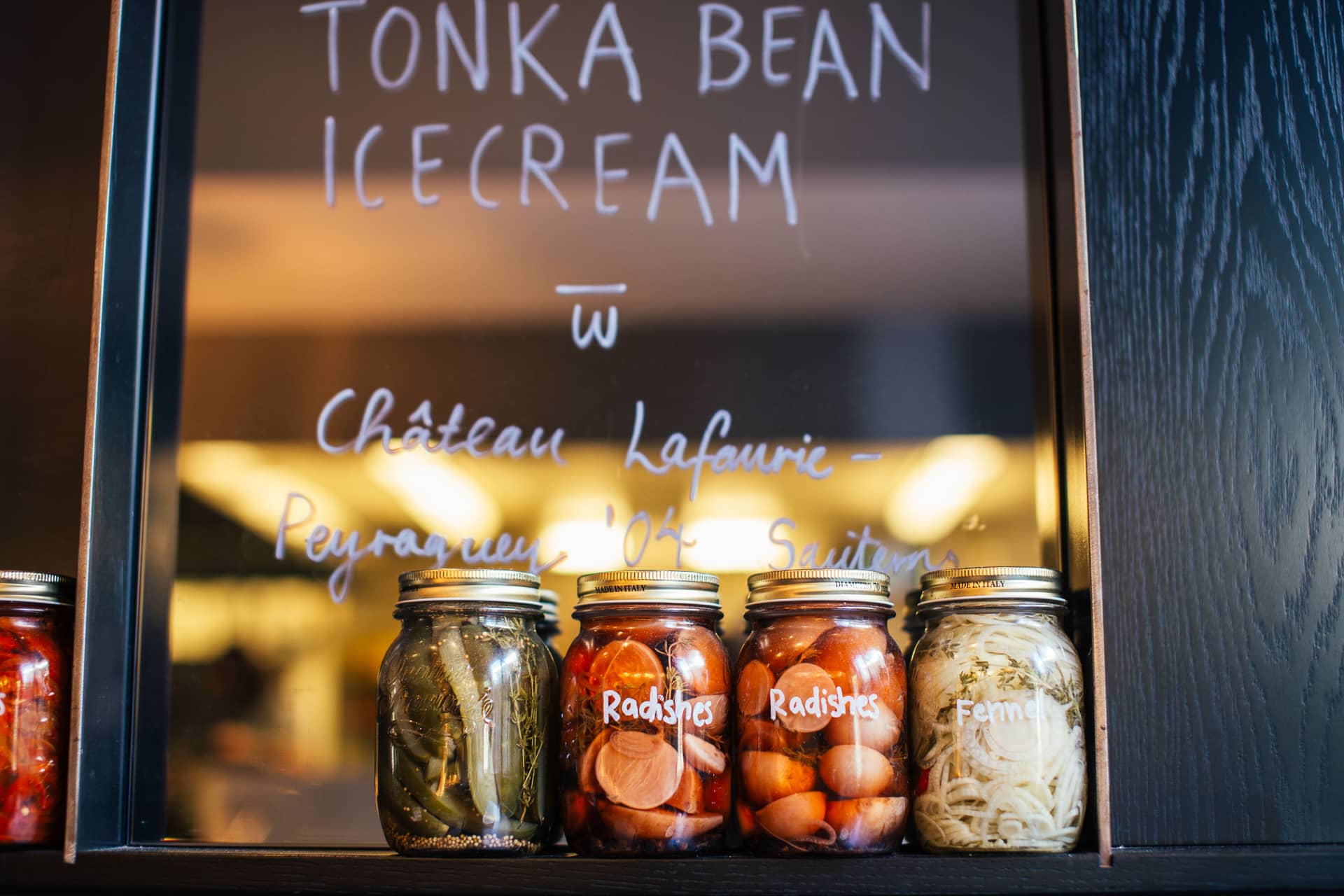 Glass jars of pickled cucumbers and vegetables on a shelf