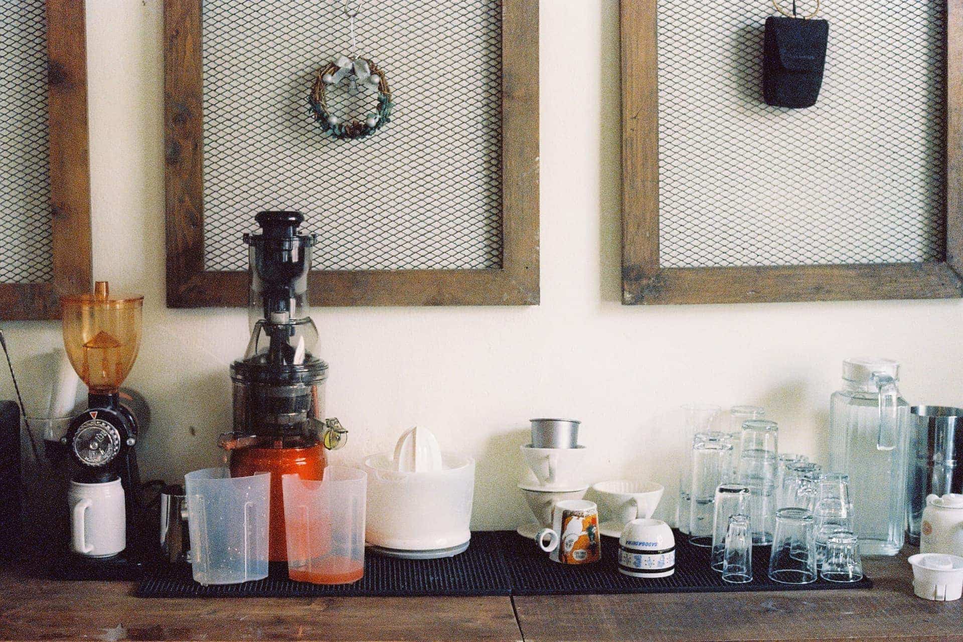 A kitchen counter with a juicer, glasses and storage containers