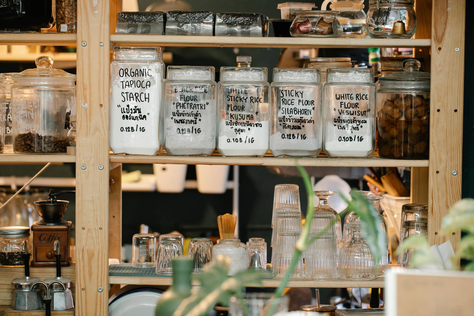 Glass jars of dry food stored on a wooden shelf