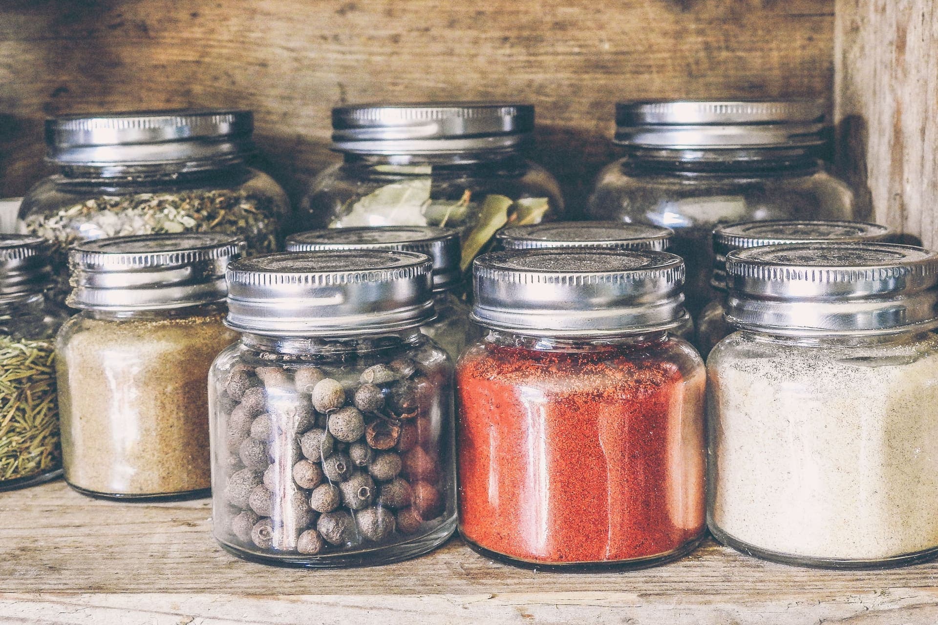 Old glass preserving jars with metal closures on a wooden shelf