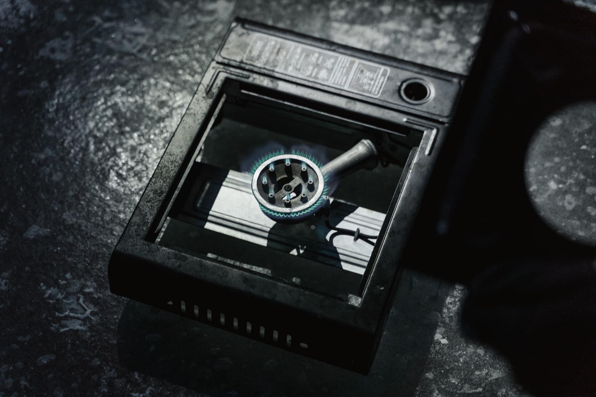 A portable stove burner with a lit blue flame