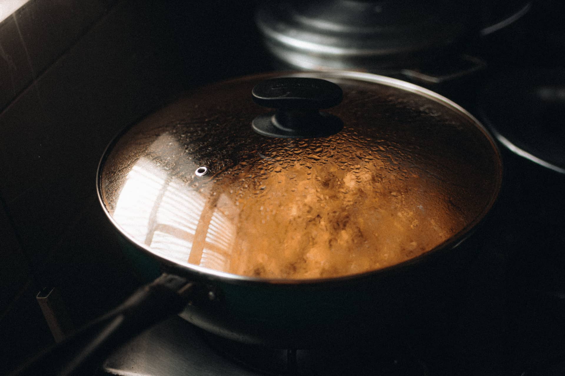 A steaming lidded pan on a stovetop