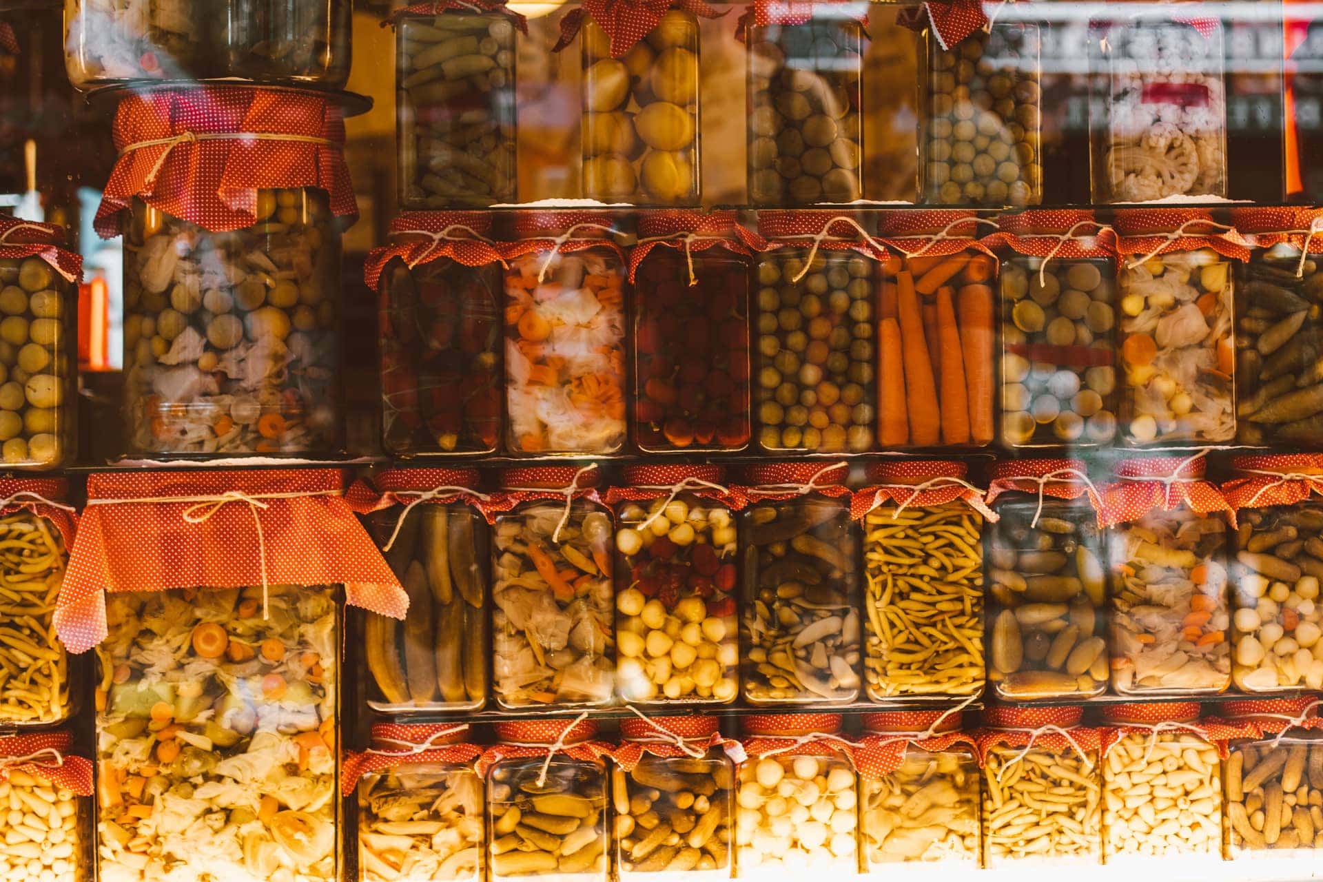 Rows of preserved vegetables in glass jars on shelves