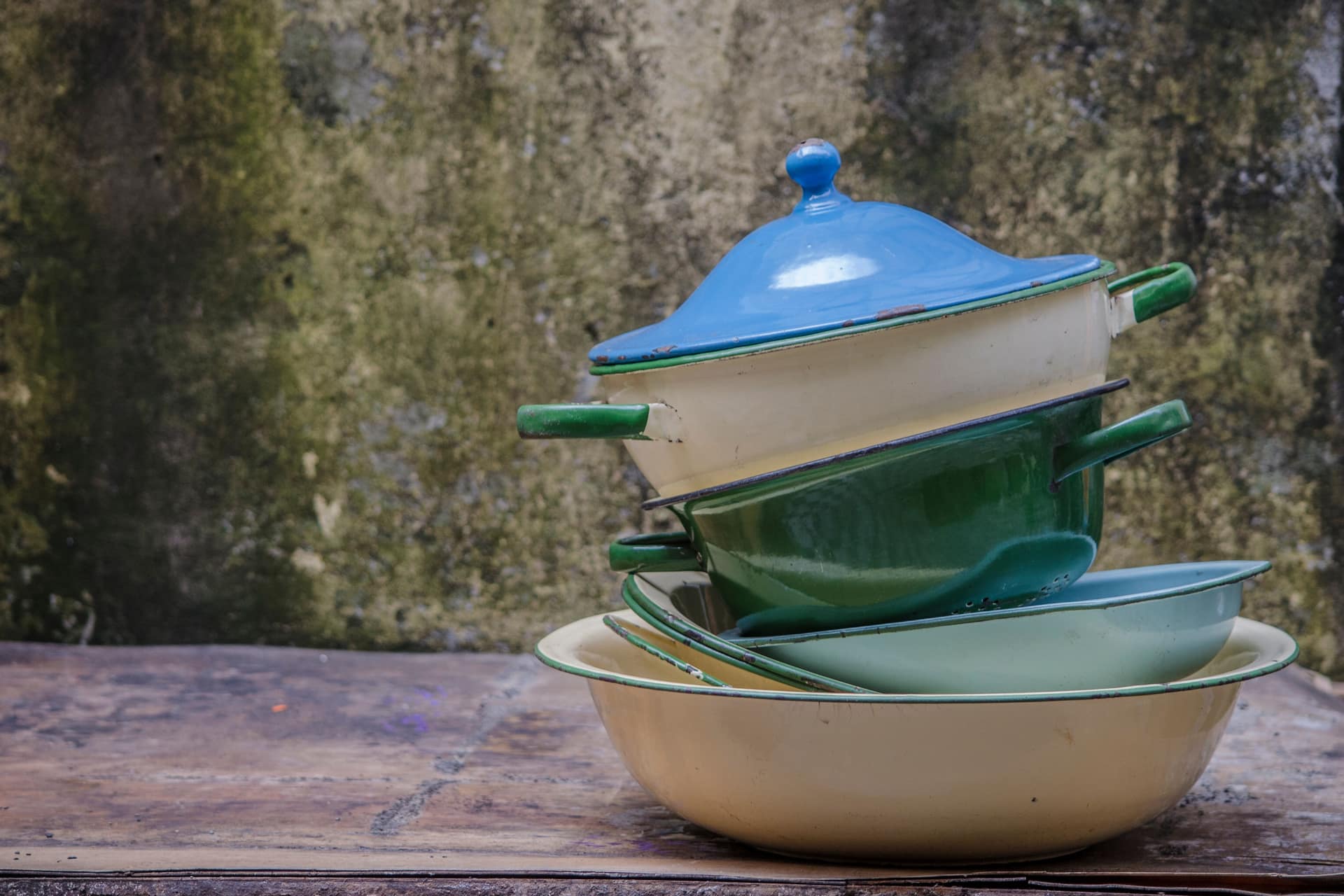 A stack of colorful vintage enamel pots and pans outdoors