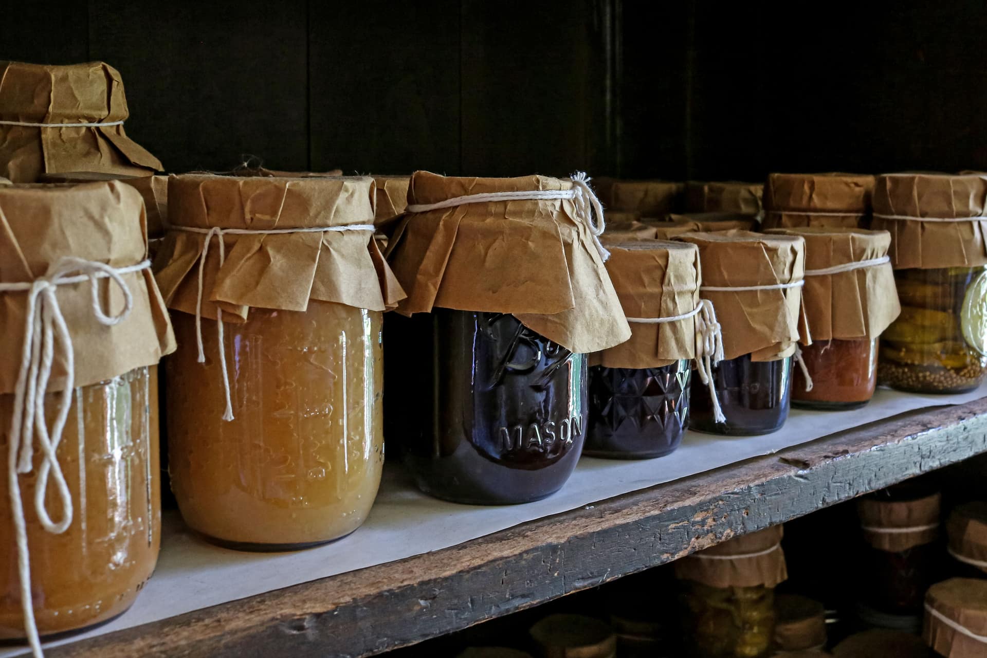 Assorted preserved foods in glass jars on a wooden shelf